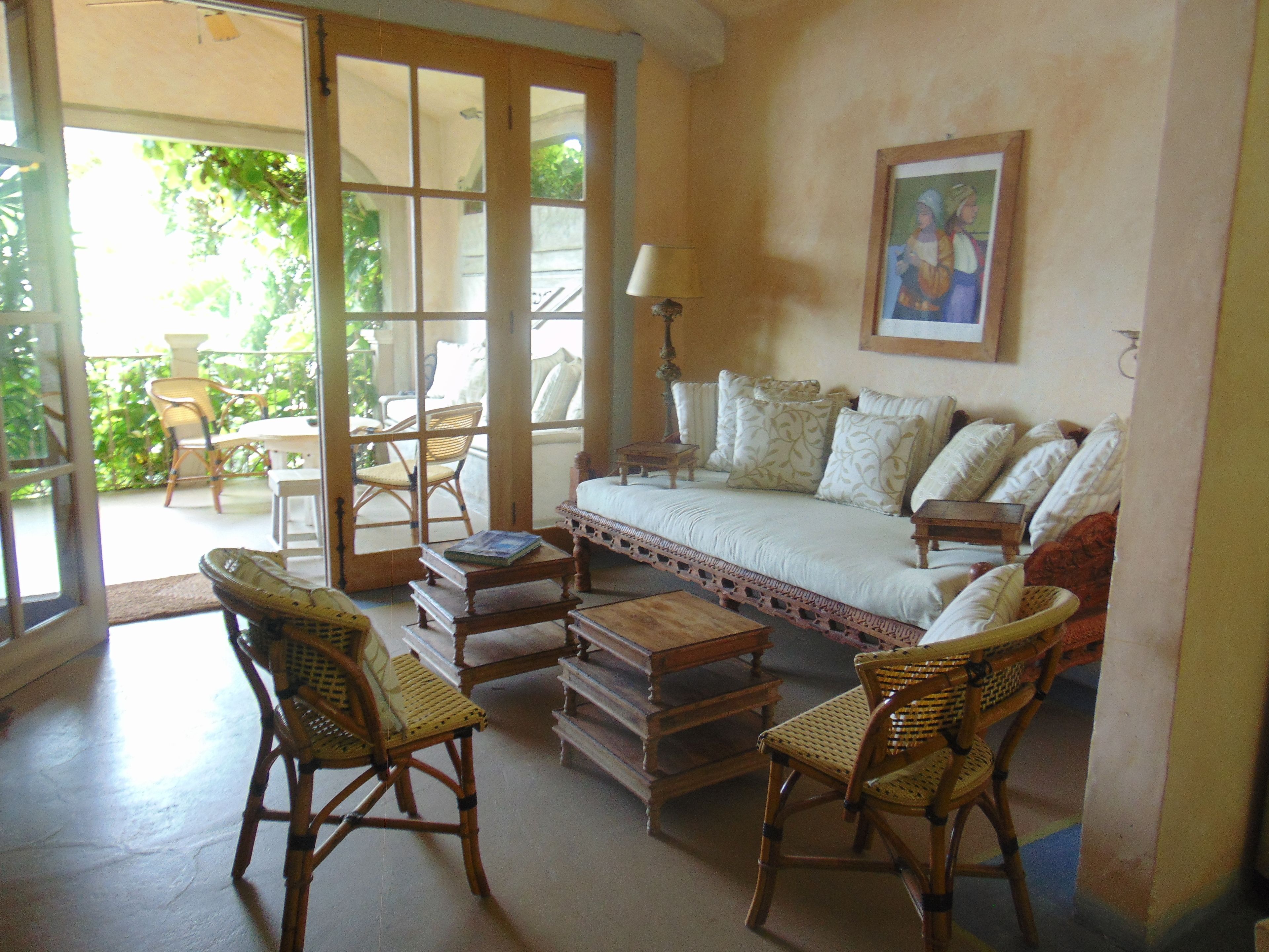 A cozy living room with a sofa, two wicker chairs, a coffee table, and a bookshelf.