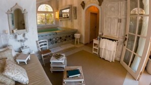 Una habitación amplia con una bañera grande, un sofá, una mesita y un armario.