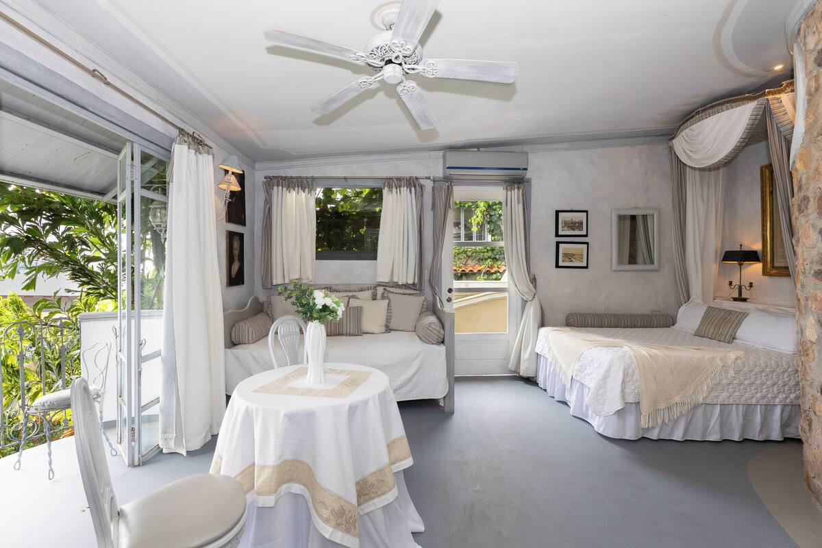 Ein Schlafzimmer mit zwei Betten, einem Deckenventilator und einem Balkon mit einem Stuhl.