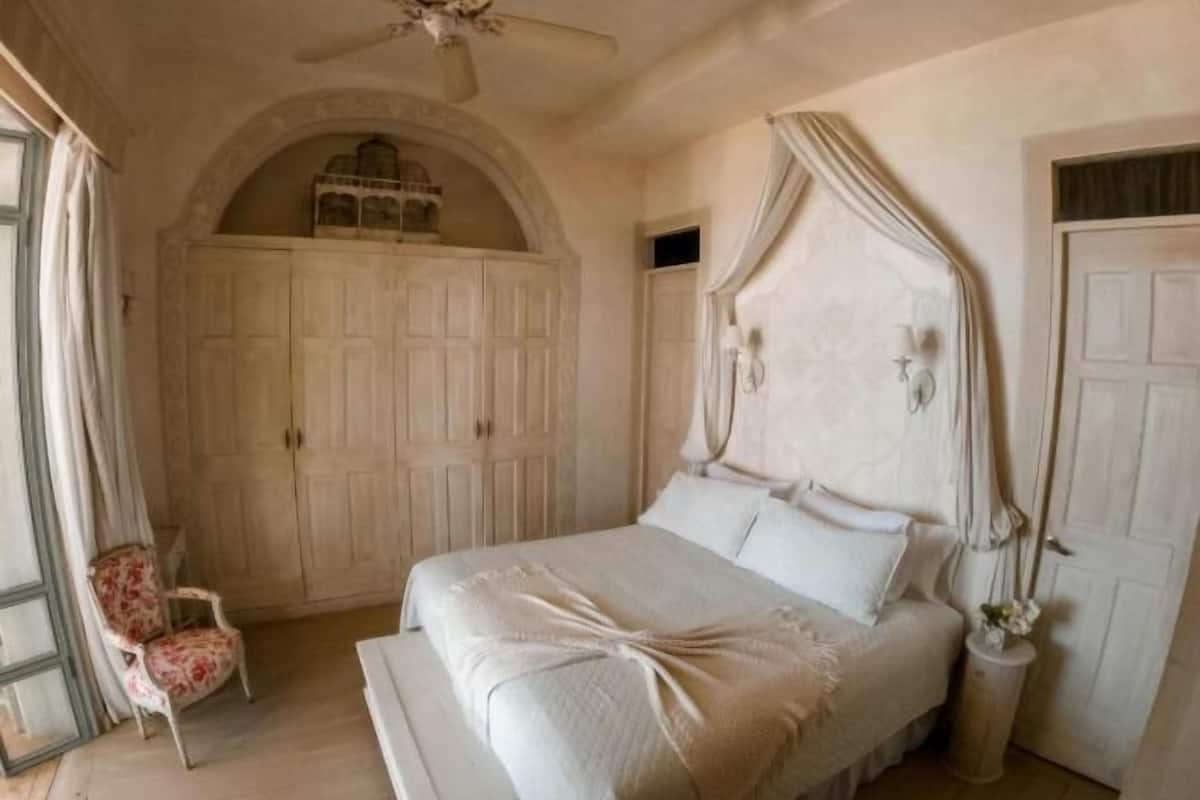 Ein Schlafzimmer mit Bett, Stuhl, Deckenventilator und Kleiderschrank.