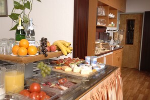 Un bufé con diversas opciones de comida, entre ellas frutas, quesos y carnes.