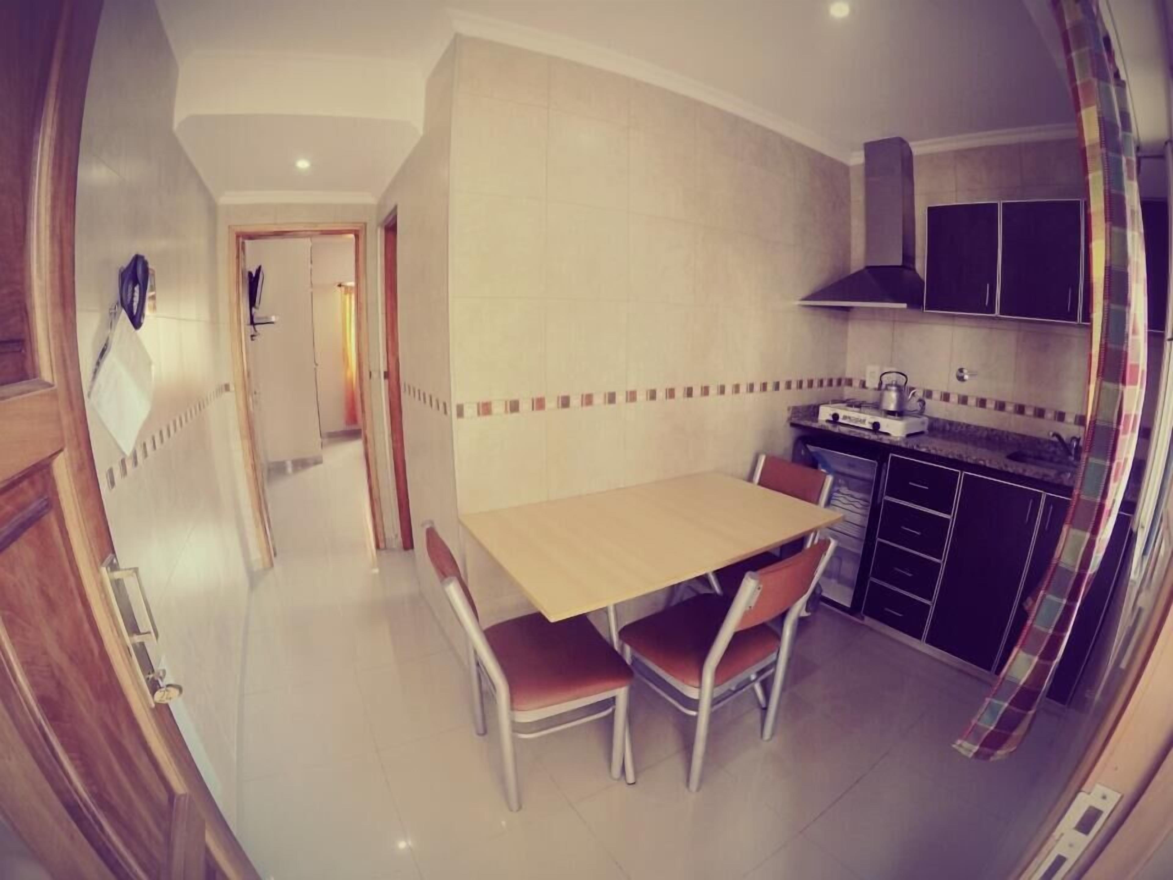 A compact kitchen with a dining table and chairs, a stove, and cabinets.