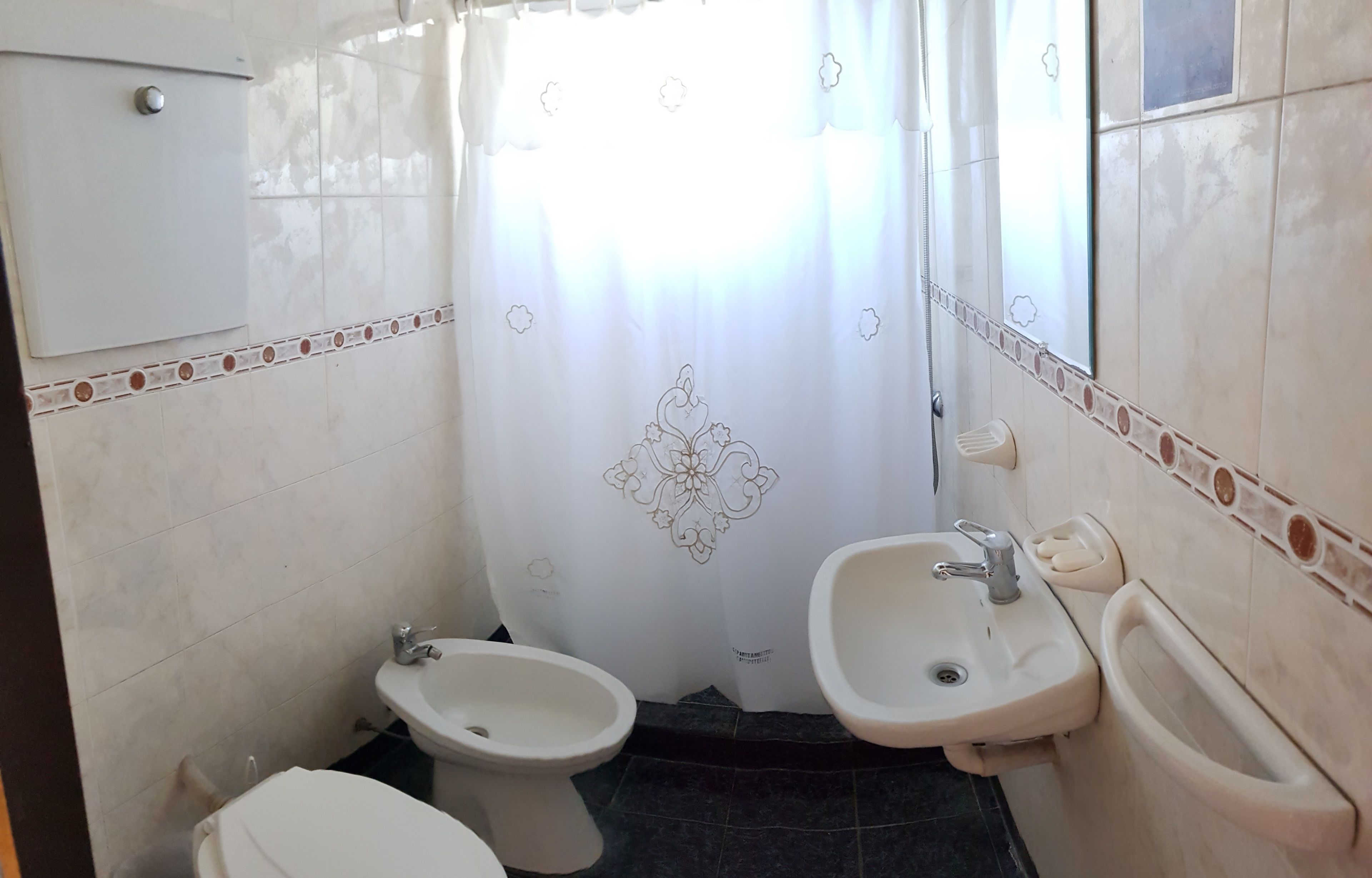 Un baño con inodoro, bidé y dos lavamanos.