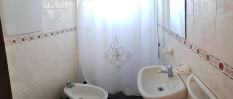 Un baño con inodoro, bidé y dos lavamanos.