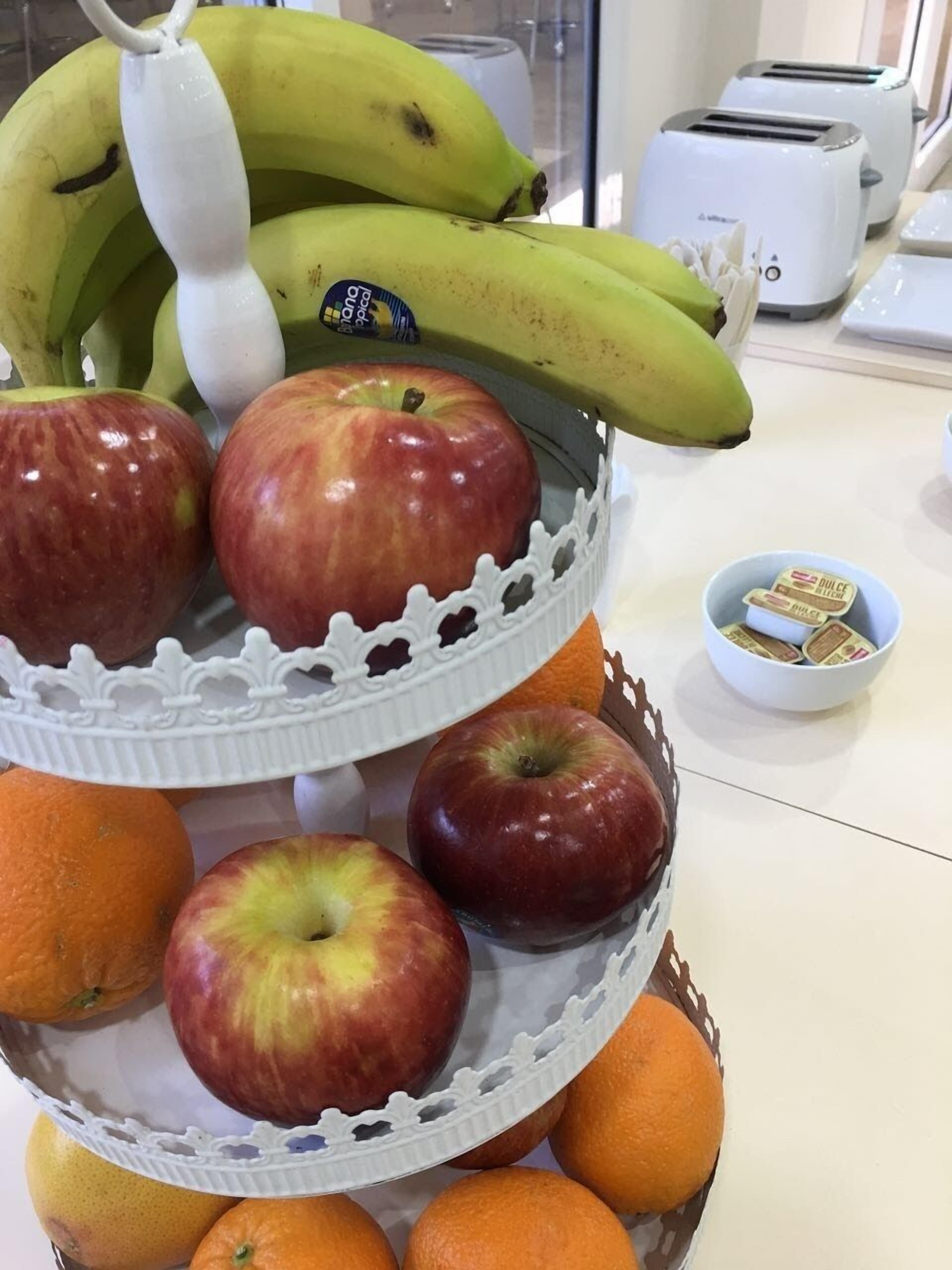 Una cesta de frutas con manzanas, naranjas y plátanos sobre una encimera de cocina.