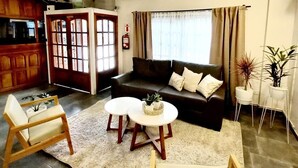 A living room with a sofa, two small tables, a chair, and a decorative plant. - Departamentos Campitelli (General Pacheco)