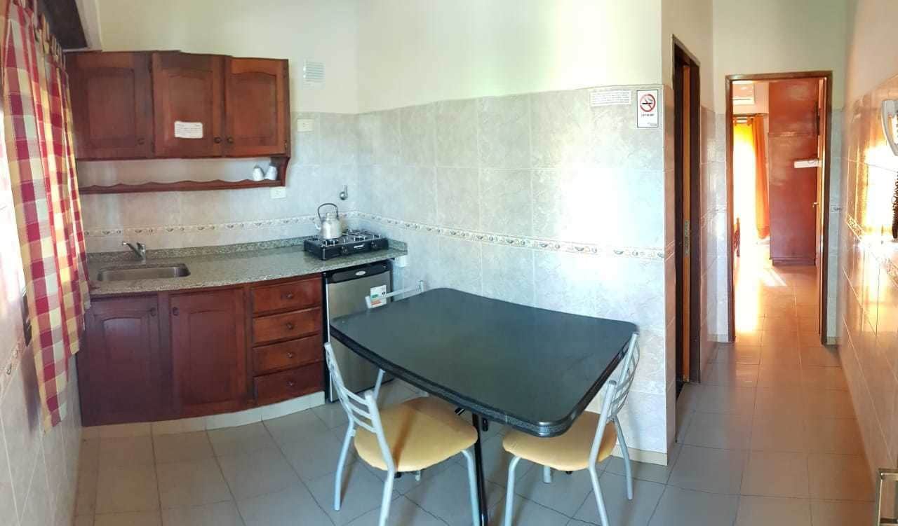 Une cuisine compacte avec des meubles en bois, une cuisinière à gaz et une petite table à manger avec deux chaises.