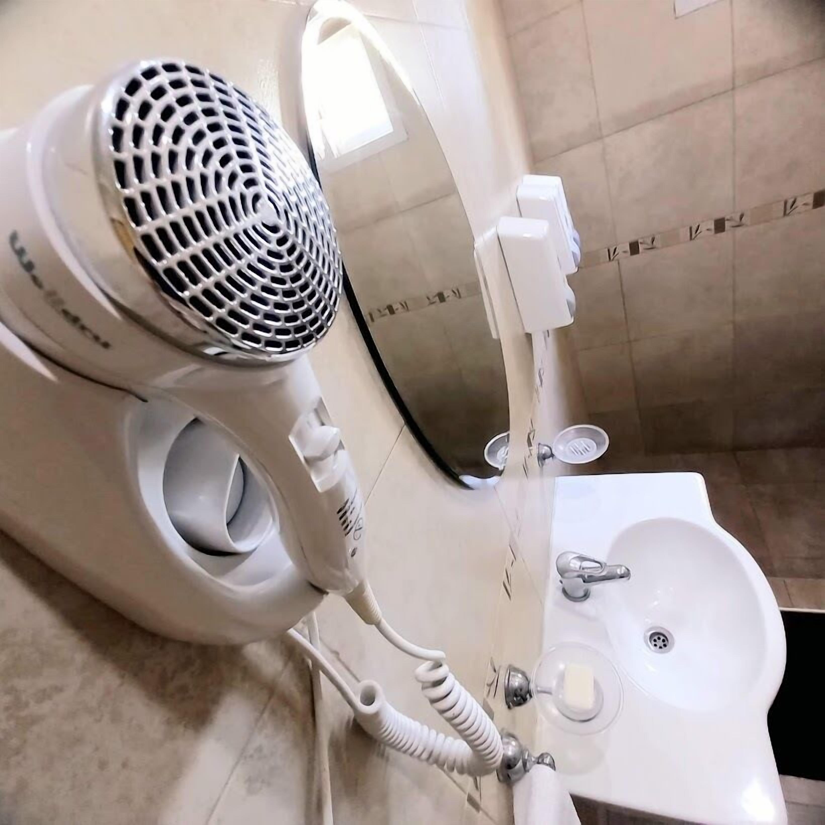 A bathroom with a hairdryer, a sink, and a mirror.