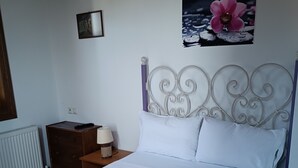 Uma cama bem arrumada com lençóis brancos, um painel decorativo e uma imagem de uma flor rosa pendurada na parede.