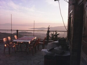 An outdoor patio with a table and chairs, overlooking a scenic view of mountains and a body of water. - Archontiko Kirmili (Volos)