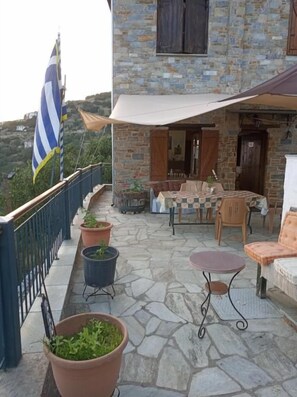 A stone building with a balcony, outdoor furniture, and potted plants. - Archontiko Kirmili (Volos)
