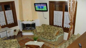 Uma sala de estar com sofá, poltrona, mesa de centro e televisão na parede.