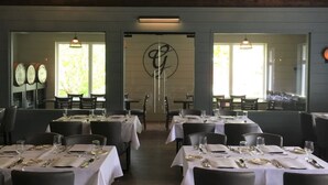 Un restaurante con mesas dispuestas para comer, un espejo grande y un reloj en la pared.