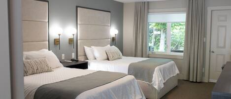 A hotel room with two beds, a large window with curtains, and a door.