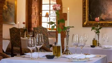 Una mesa de comedor dispuesta con copas de vino, una vela y un florero con una rosa.