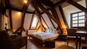 A cozy attic bedroom with a wooden bed, a desk, and a chair. - Hotel Der Schafhof Amorbach (Amorbach)