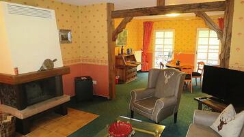 Un salon chaleureux avec une cheminée, un fauteuil confortable, un canapé et un téléviseur.