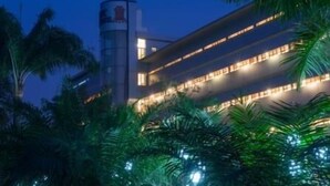 A multi-story hotel with a prominent cylindrical tower and illuminated windows. - Olympic Palace (Brazzaville)