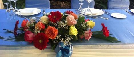 Une table mise pour un repas, agrémentée d’un centre de table floral, d’une nappe bleue et de verres transparents.