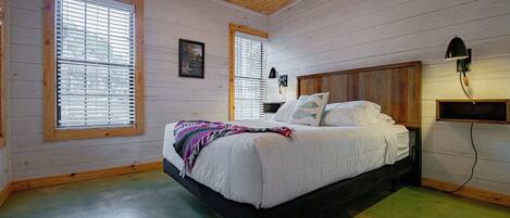 A bedroom with a bed, two windows, a ceiling fan, and a nightstand.