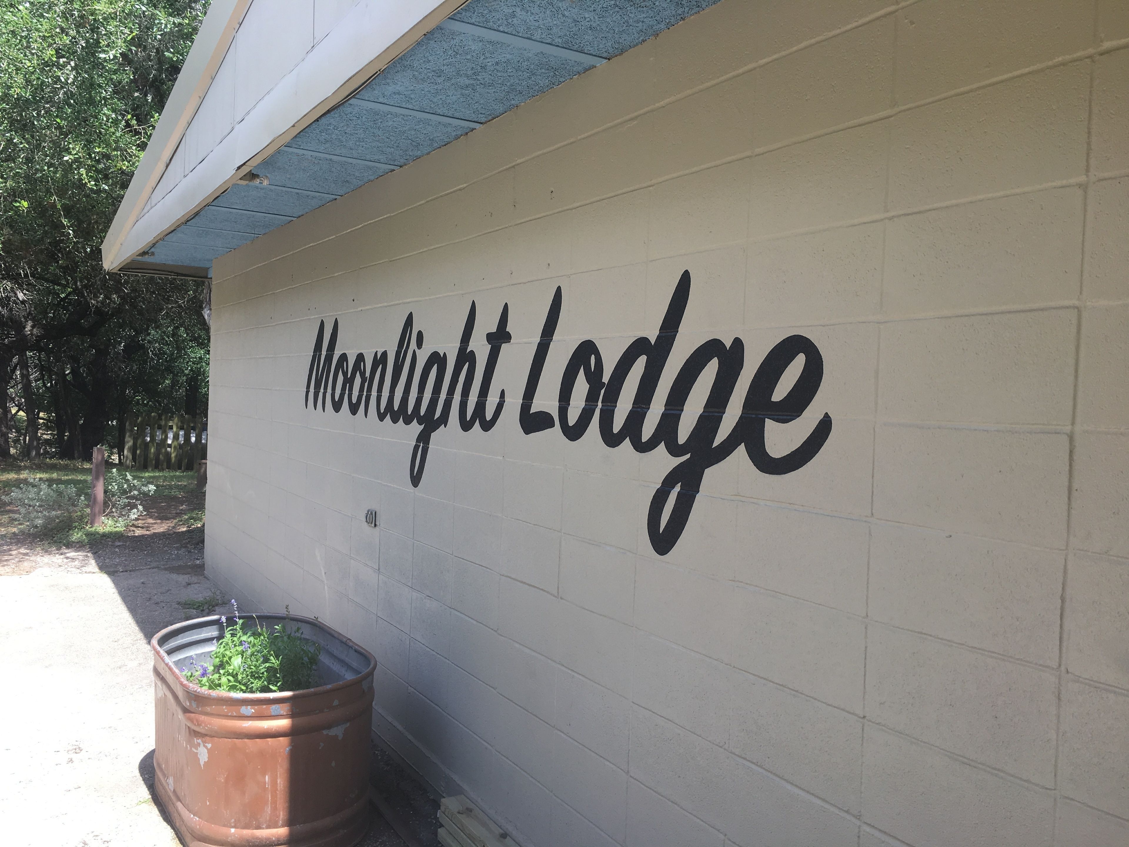 Een muur met de tekst 'Moonlight Lodge' in een groot, sierlijk lettertype.