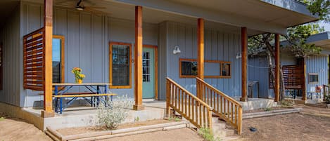 Une maison à deux étages avec un porche couvert, des colonnes en bois et une porte d’entrée.