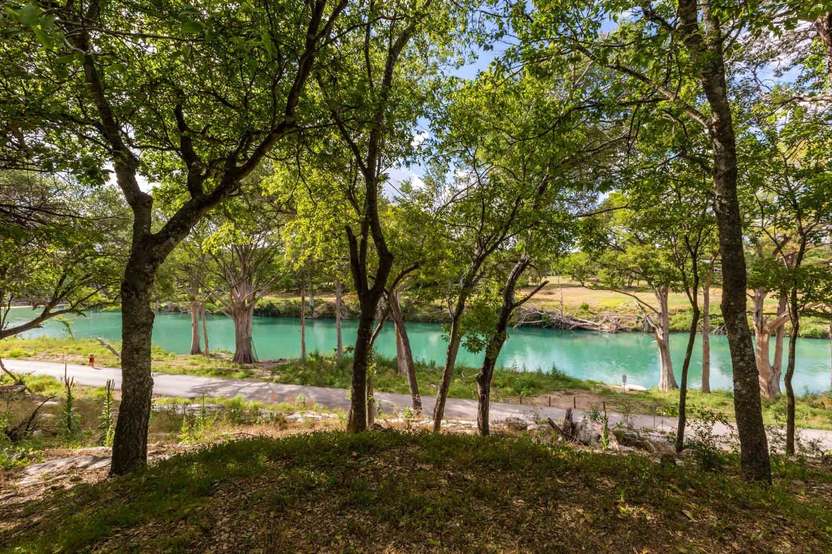 Paisagem natural com um lago, árvores e uma estrada.