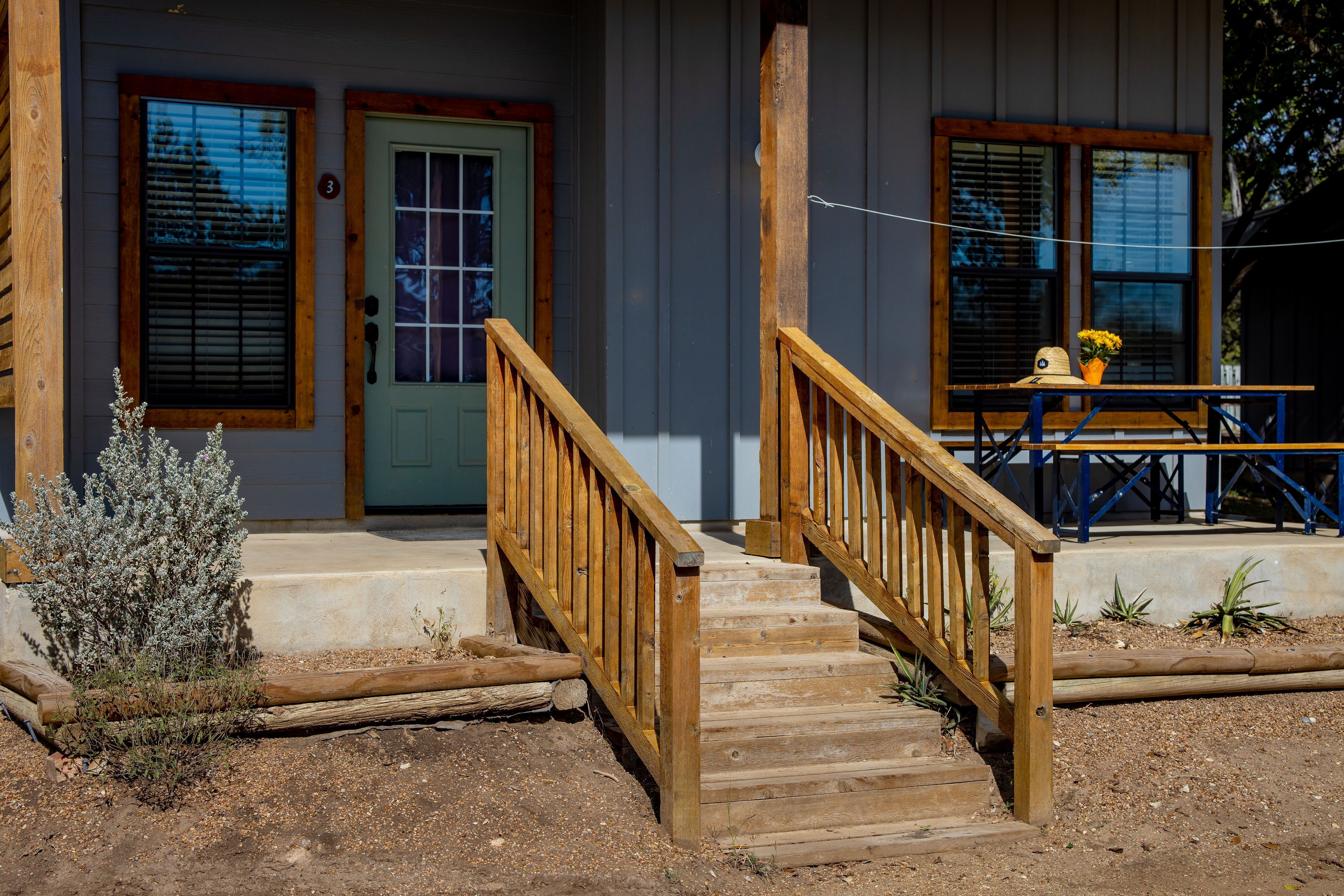 A wooden staircase leading to a porch with a bench and a table.