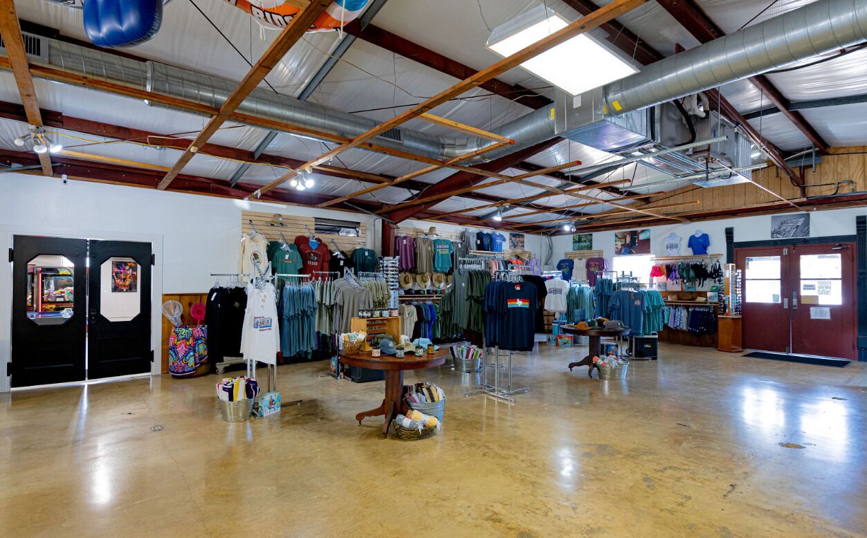 A spacious indoor market with various stalls selling clothing and accessories.