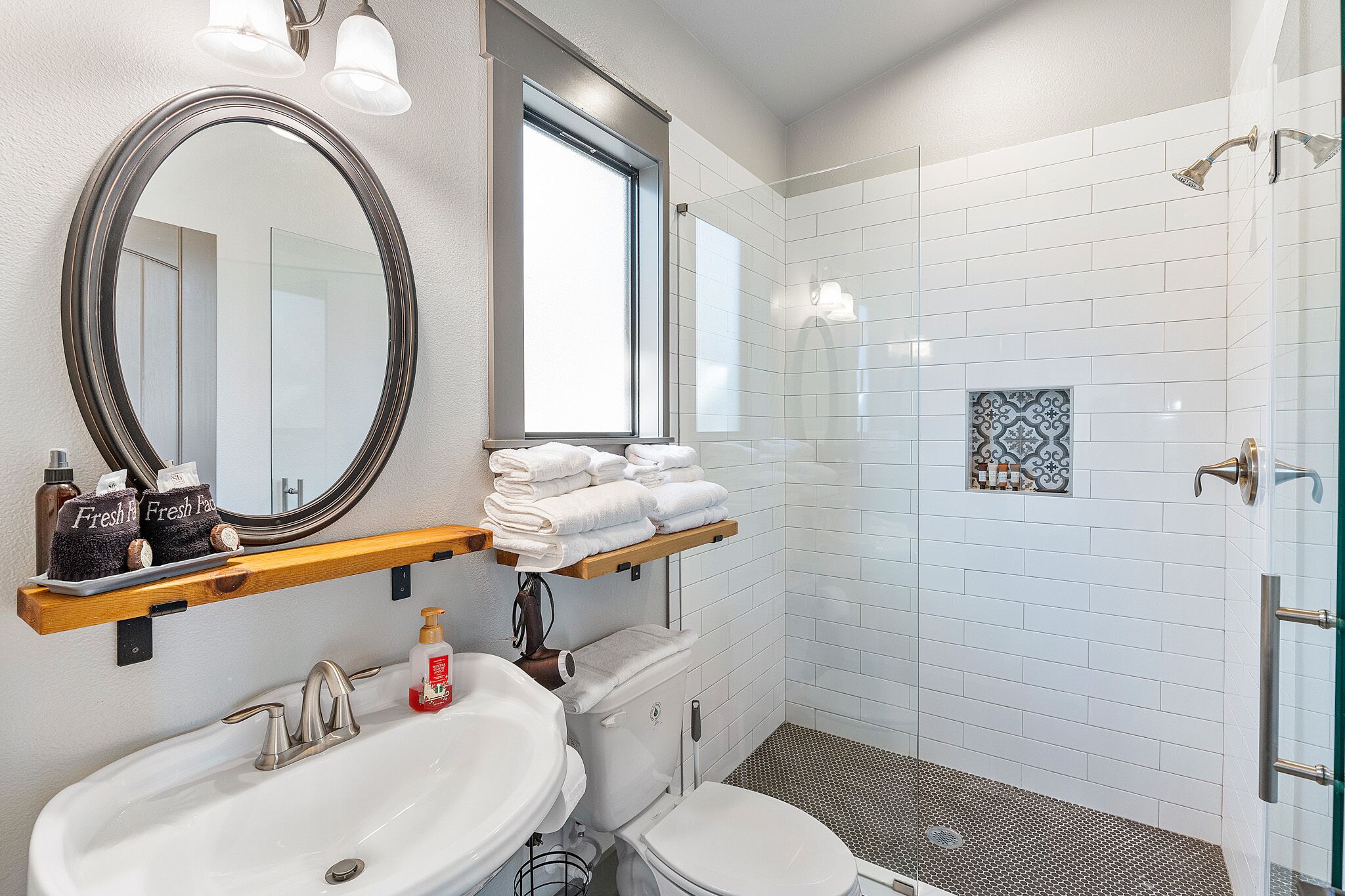 Une salle de bain moderne avec un grand miroir, un lavabo, des toilettes et un espace douche.