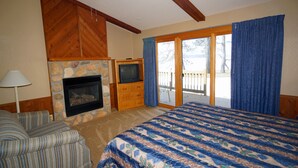 A bedroom with a large bed, a fireplace, a television, and a sliding glass door to the outside. - Kavanaugh's Sylvan Lake Resort (Brainerd)