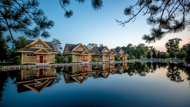 A row of houses with a reflective water body in the foreground. - Kavanaugh's Sylvan Lake Resort (Brainerd)