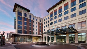 A hotel with a modern design, featuring a prominent entrance with a glass canopy and a central water feature. - Embassy Suites by Hilton Amarillo Downtown (Amarillo)