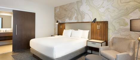 A modern hotel room with a large bed, a nightstand, a chair, and a wall with a topographic map design.