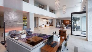 A spacious lobby with a modern design, featuring a seating area with sofas and chairs, a reception desk, and a large chandelier. - Embassy Suites by Hilton Amarillo Downtown (Amarillo)