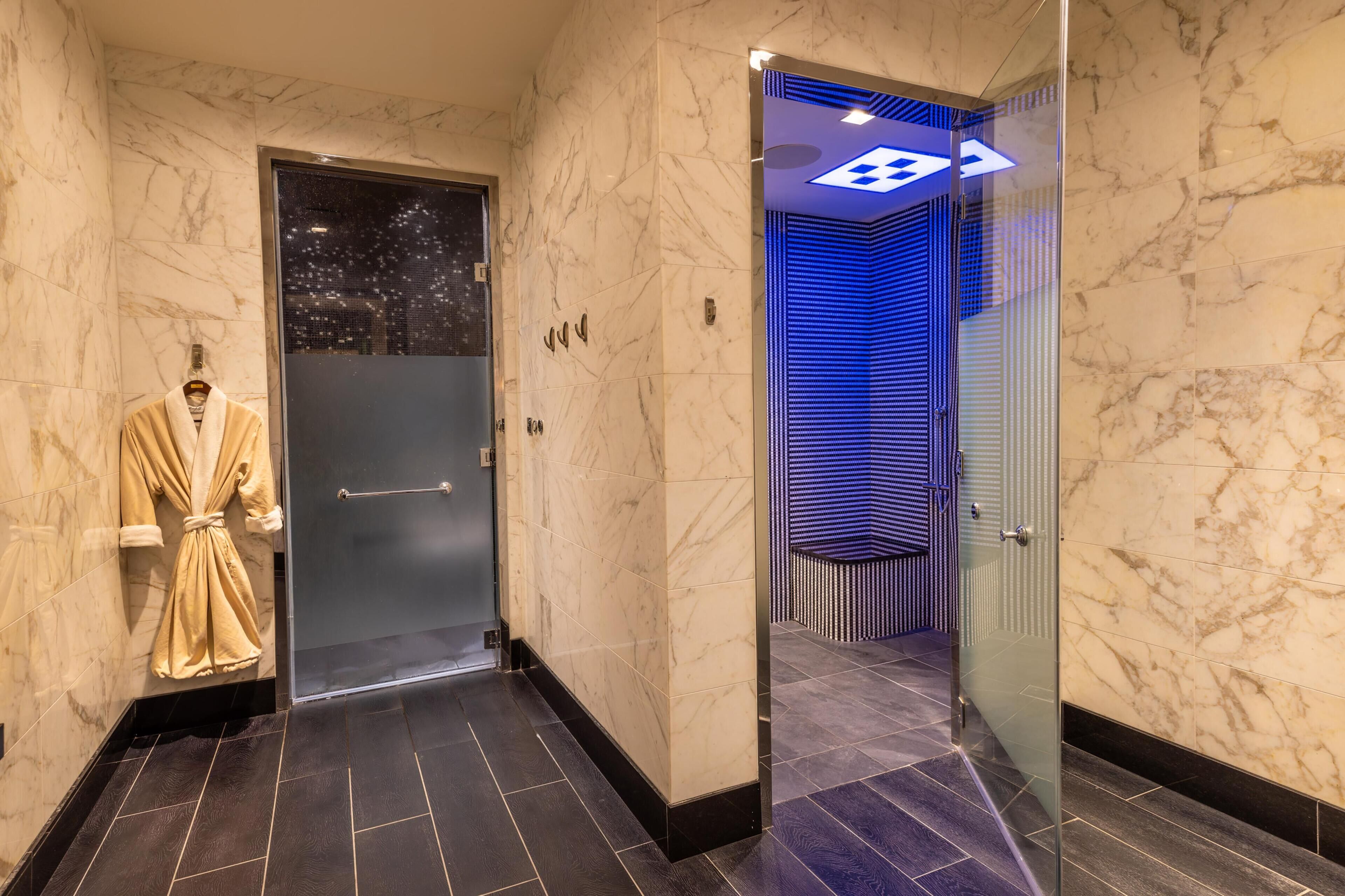 A hallway with marble walls, a glass door, and a robe hanging on the wall.