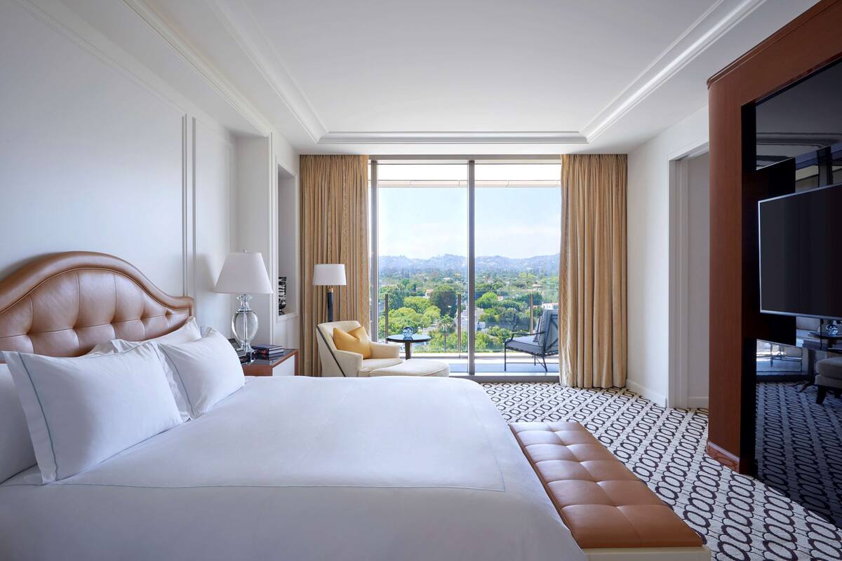 Une chambre d’hôtel avec un grand lit, un canapé, une télévision et un balcon offrant une vue sur la ville.