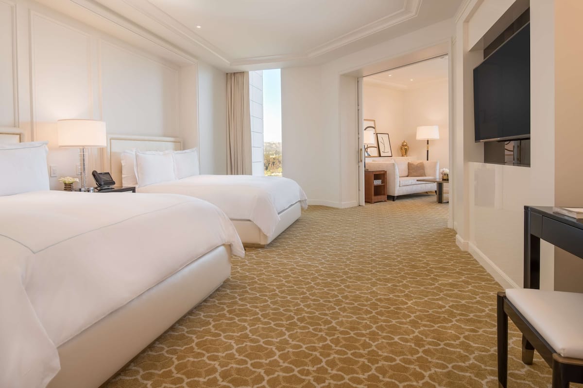 Une chambre d’hôtel avec deux lits, une télévision, un bureau et une chaise.