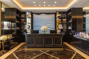 A reception desk with a marble floor, black shelving units, and a decorative wall with a wave pattern.