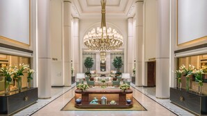 Un hall d’entrée luxueux, doté d’un comptoir de réception central, d’élégants lustres et d’une décoration symétrique.