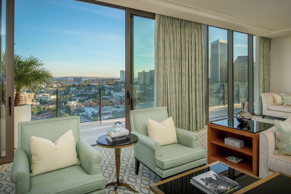 Un salon spacieux offrant une vue sur la ville, comprenant deux fauteuils, un canapé et une table basse.