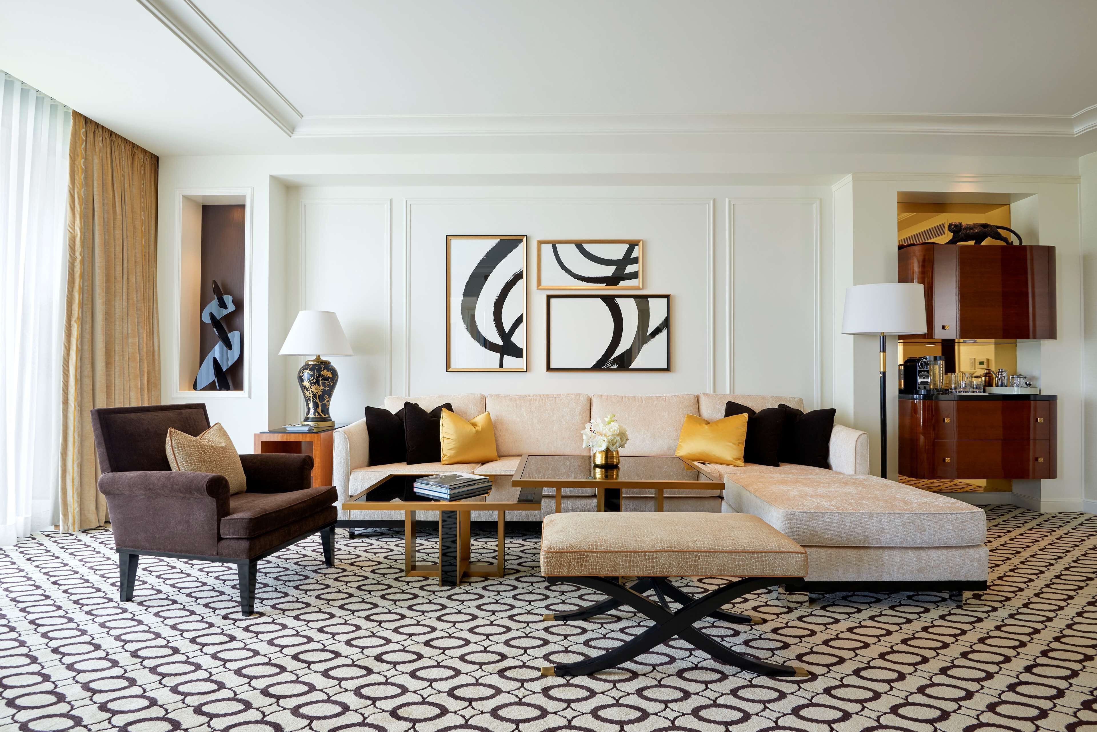 A modern living room with a sofa, armchair, and ottoman, a coffee table, and abstract wall art.