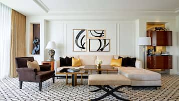A modern living room with a sofa, armchair, and ottoman, a coffee table, and abstract wall art.
