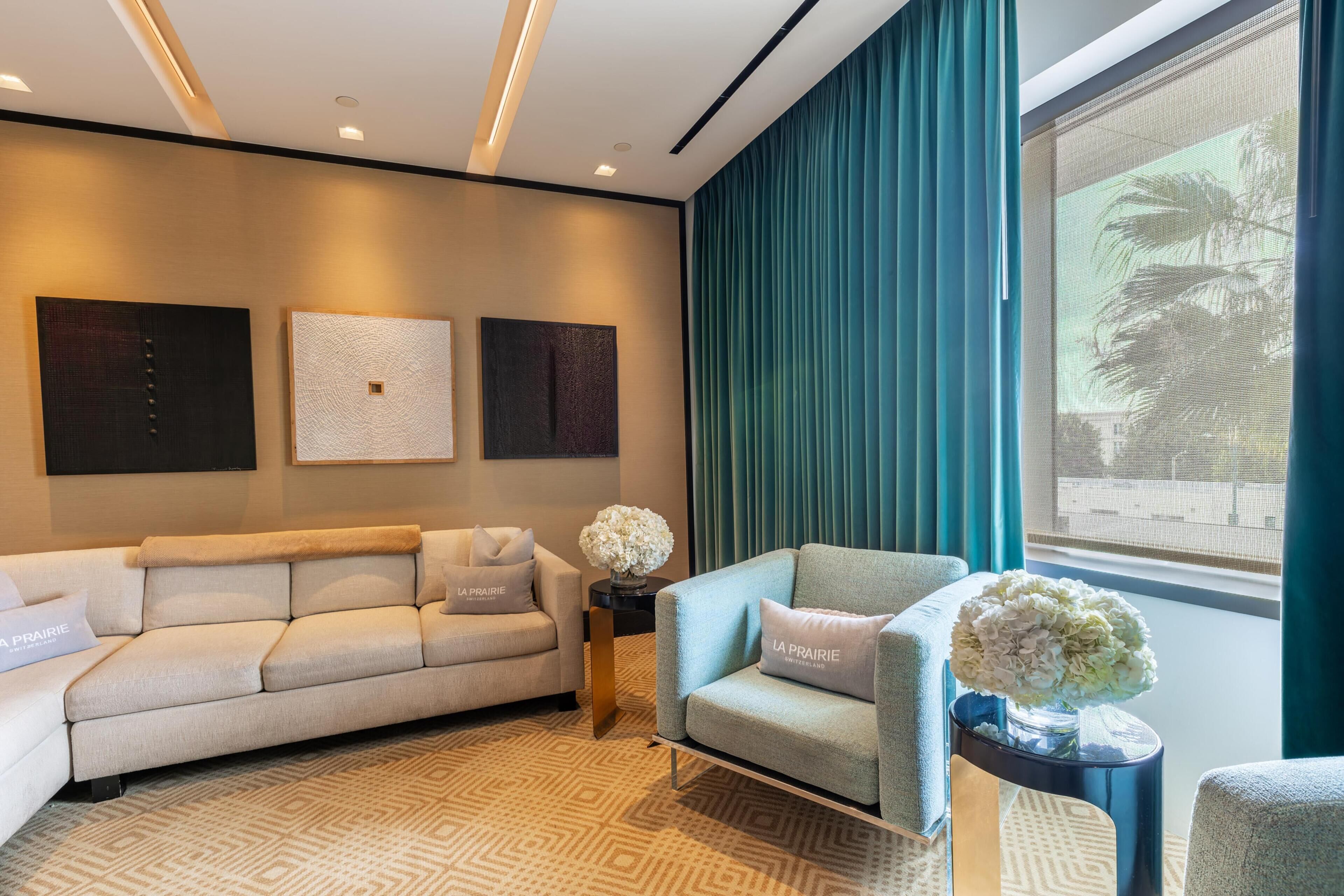 A modern living room with a sofa, armchair, and a small table with a vase.
