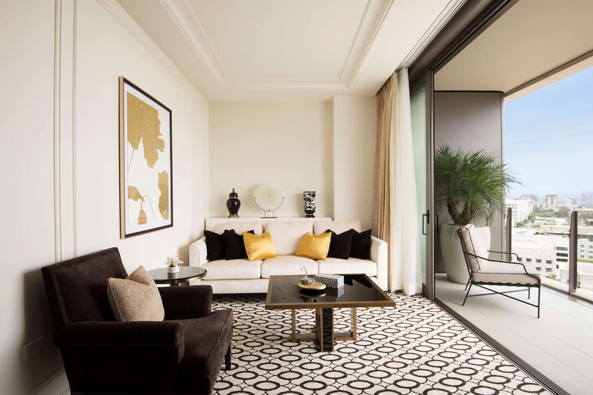 Un salon moderne avec un canapé, des fauteuils, une table basse et une grande fenêtre donnant sur la ville.