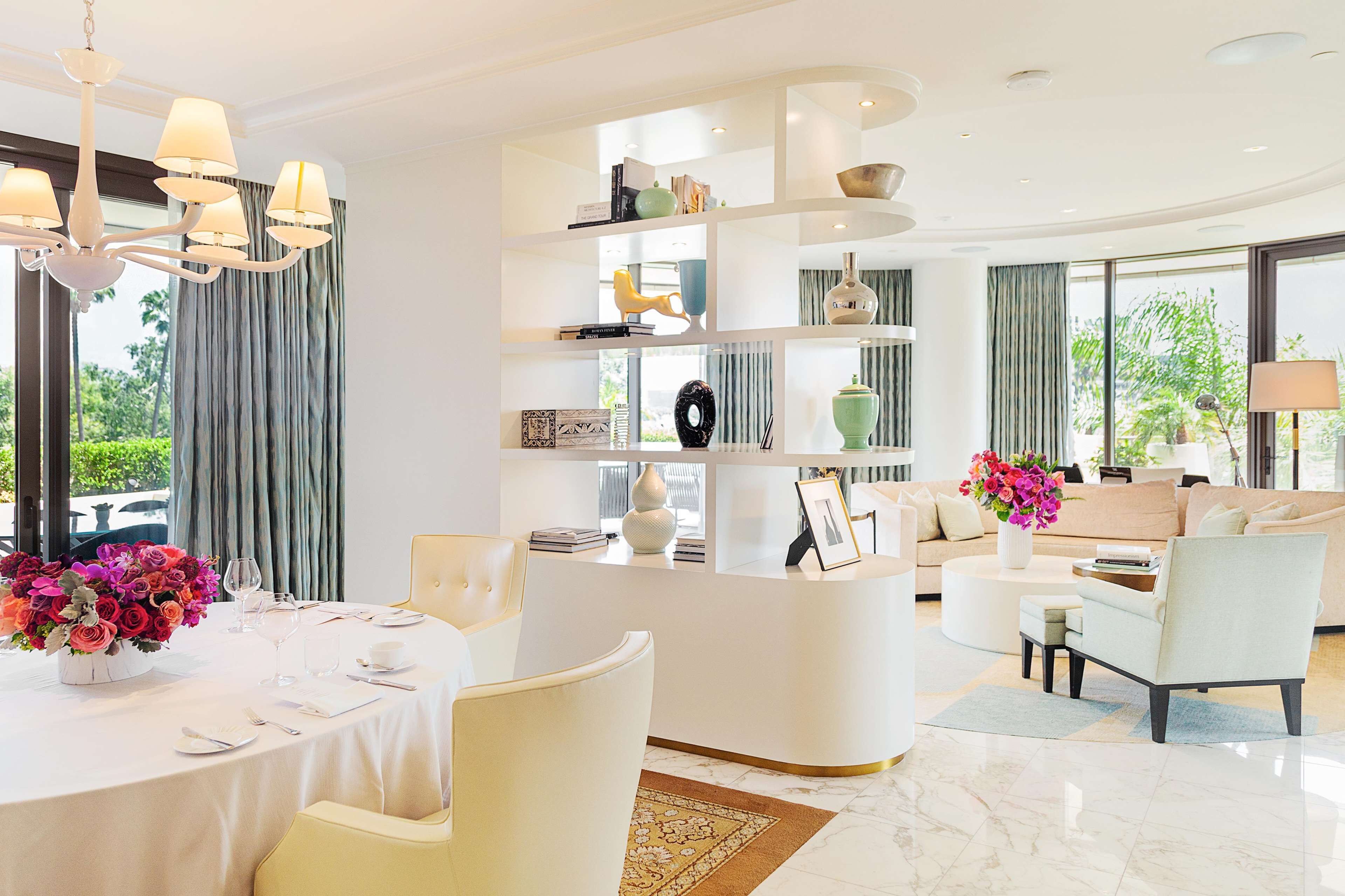 Una sala de estar moderna y luminosa, con una mesa de comedor redonda, asientos cómodos y una estantería empotrada.