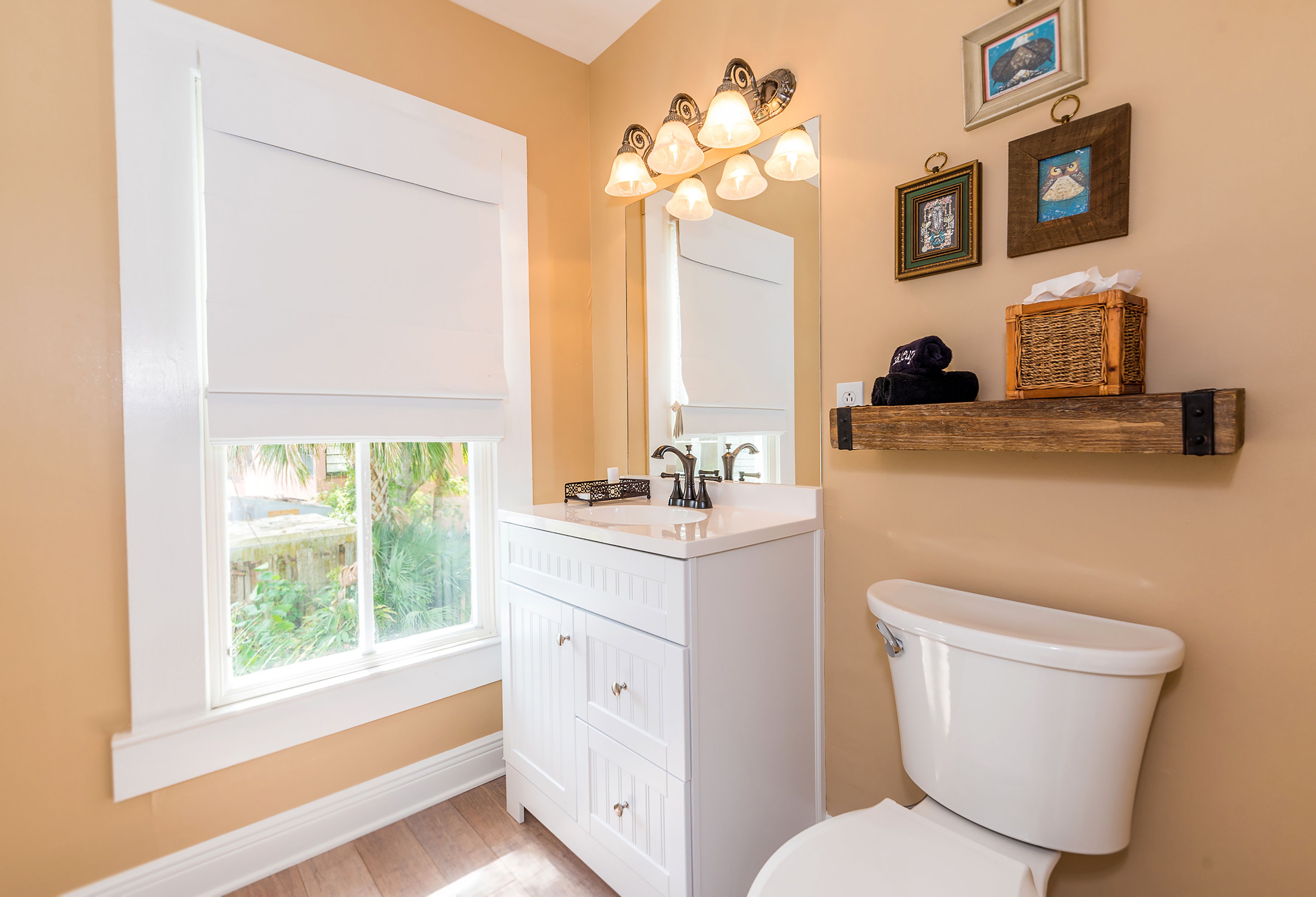 A bathroom with a window, white vanity, and a toilet.