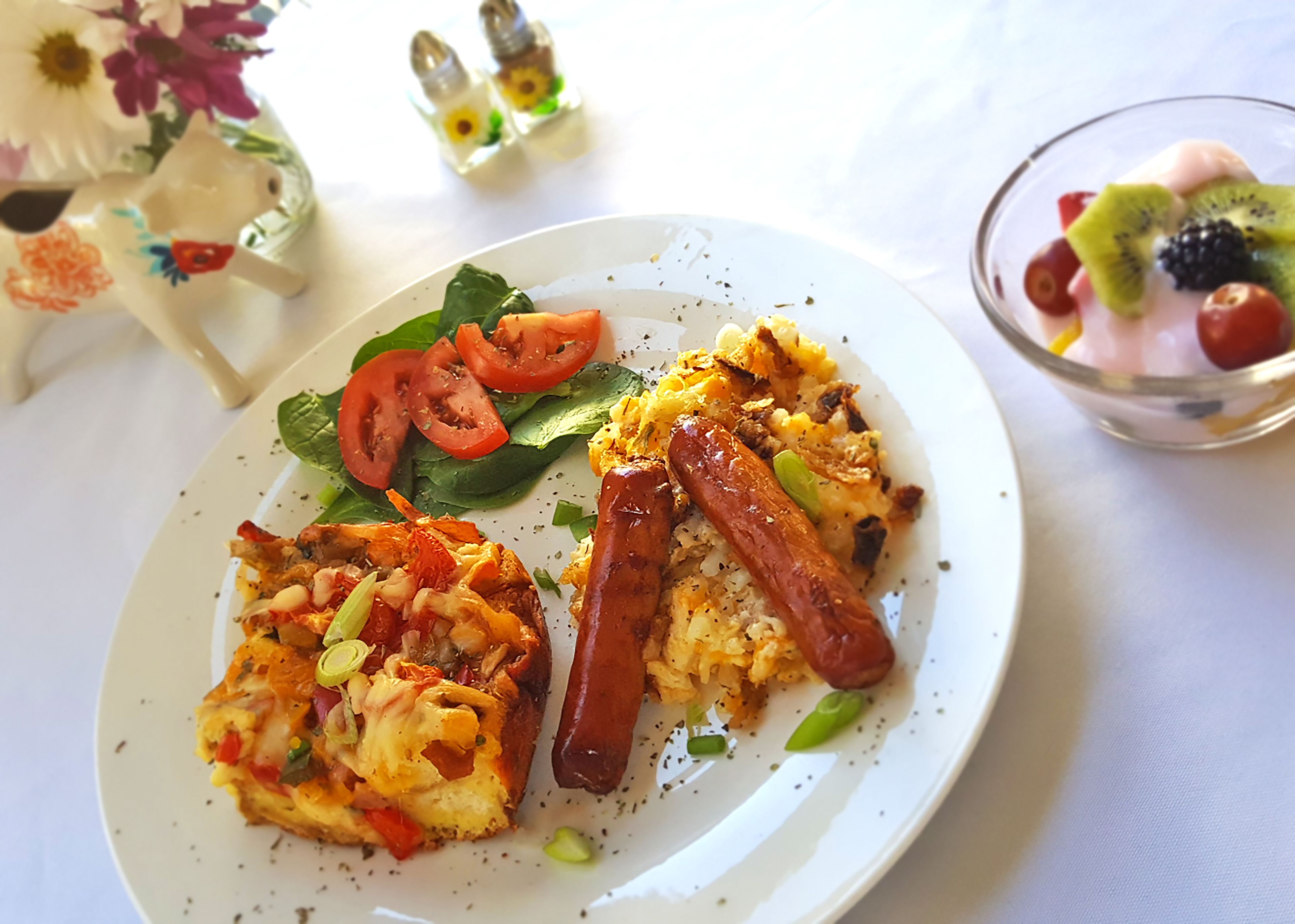 A plate with a breakfast dish, including eggs, tomatoes, spinach, and sausage.