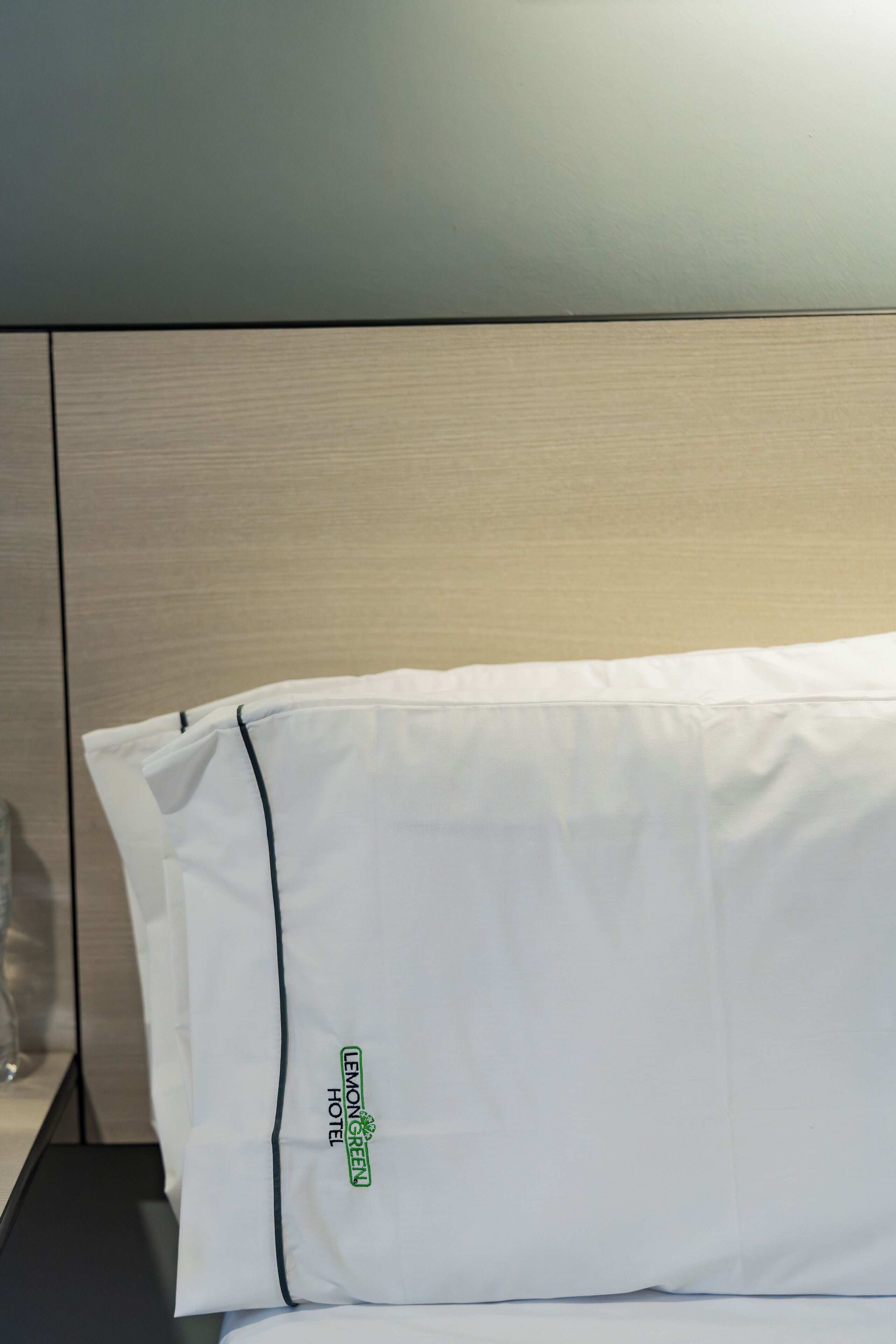 A white pillow with a logo and text indicating it is from the Lemon Green Hotel.