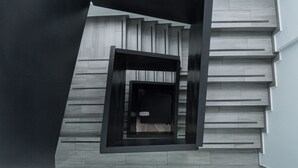 Una escalera moderna con diseño minimalista, que presenta un patrón geométrico en la pared y un elegante marco negro alrededor de los escalones.